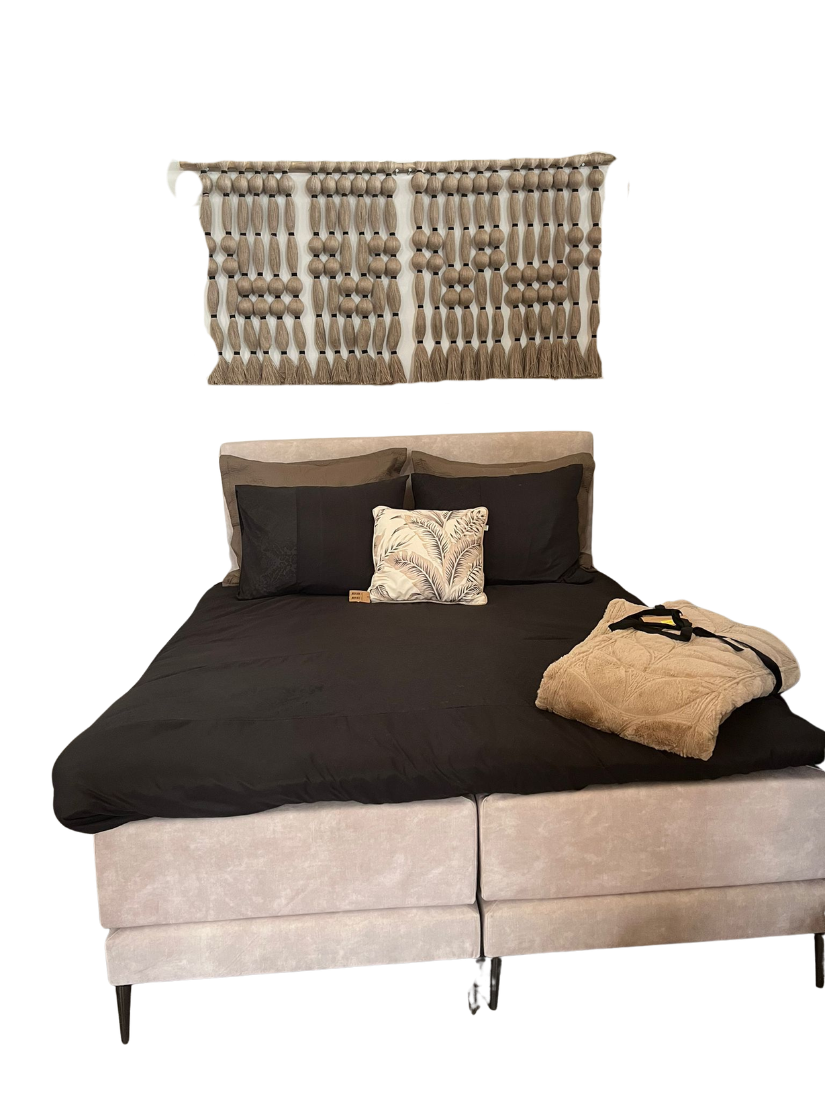 Master bedroom — dark linen boxspring with hand-knotted macramé wall hanging